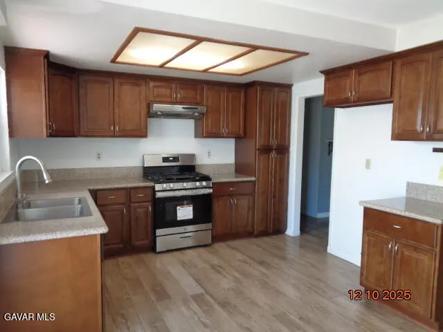 a kitchen with stainless steel appliances granite countertop a refrigerator a sink a stove a microwave and wooden cabinets