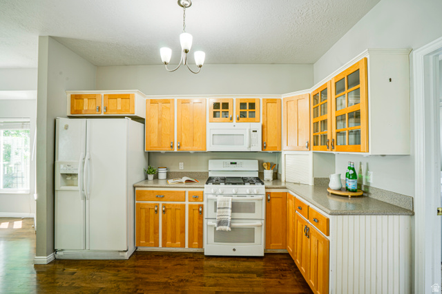 1433 Forge Way Draper, UT 84020 - Photo 11 of 29 Kitchen featuring wood-finish flooring, two-tone cabinetry with glass-front uppers, a white side-by-side refrigerator, and a white gas range with a double oven