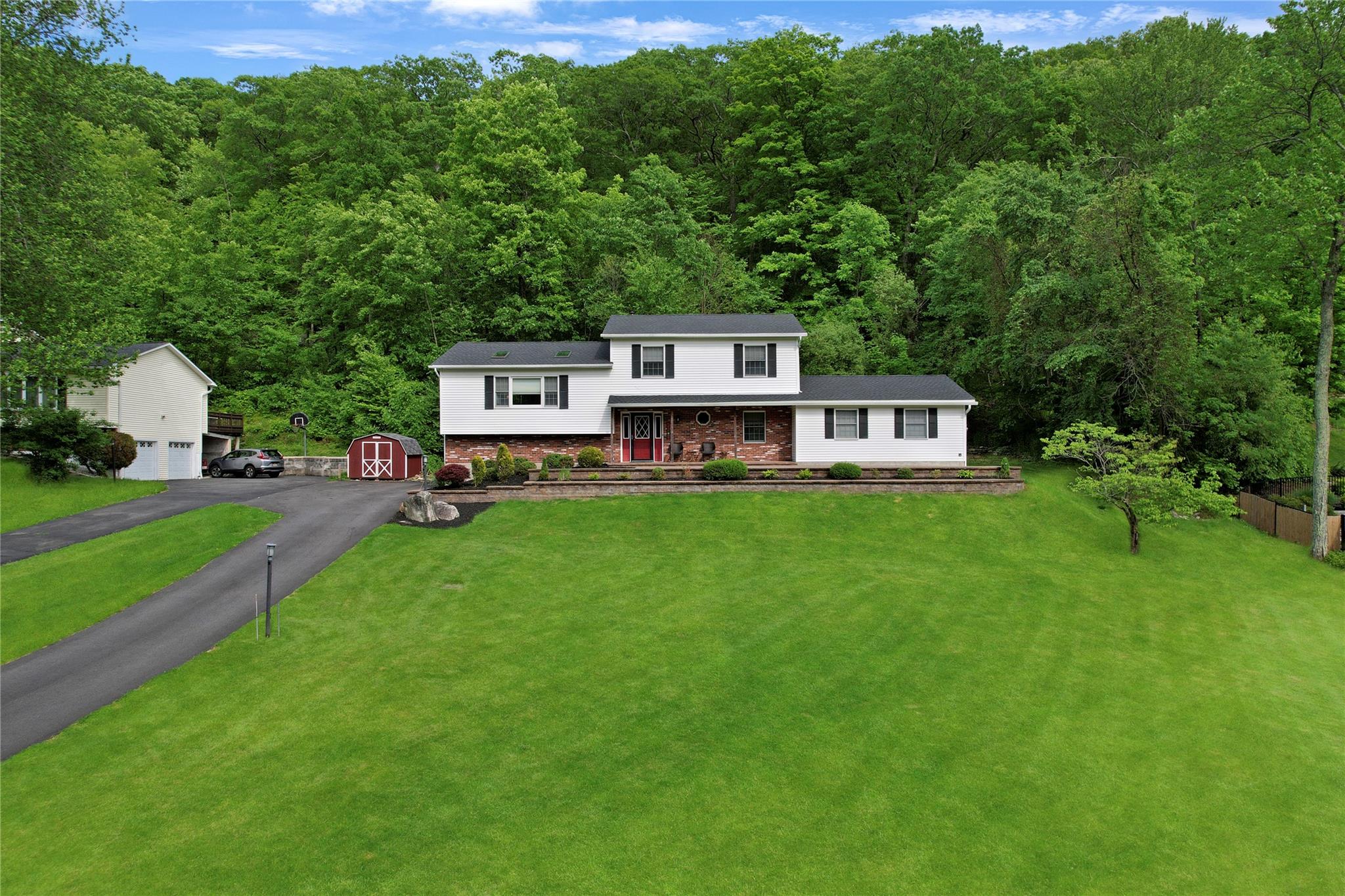 Split level home featuring a forest view, an outdoor structure, covered porch, and a storage shed