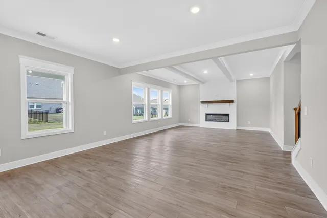a view of an empty room with window and wooden floor