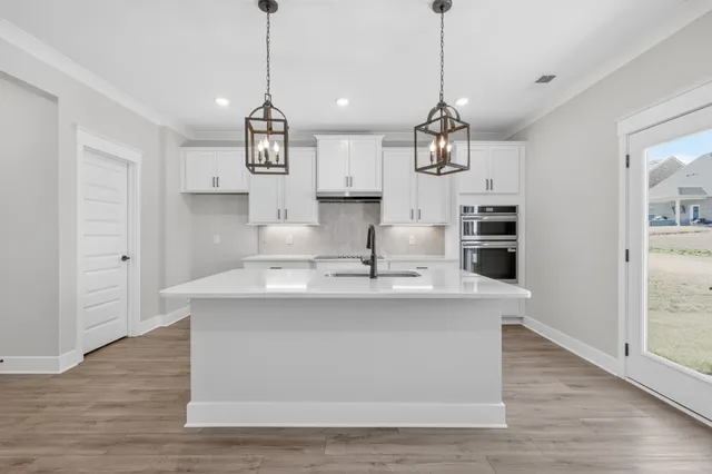 a large kitchen with kitchen island a stove a sink a center island and wooden floor