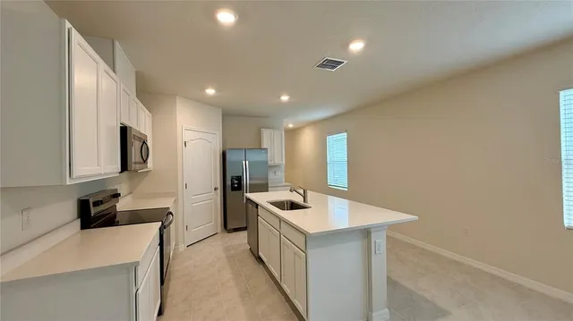 a kitchen with a sink a counter top space stainless steel appliances and cabinets