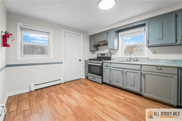 a kitchen with stainless steel appliances granite countertop a stove a sink and white cabinets
