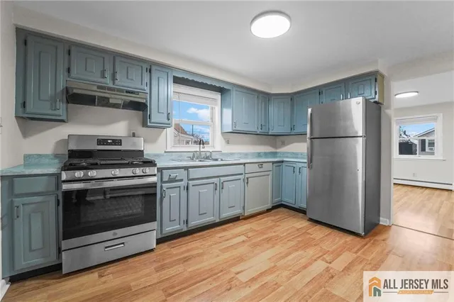 a kitchen with granite countertop a refrigerator stove and wooden floor