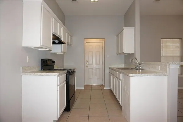a kitchen with kitchen island granite countertop a sink and white cabinets