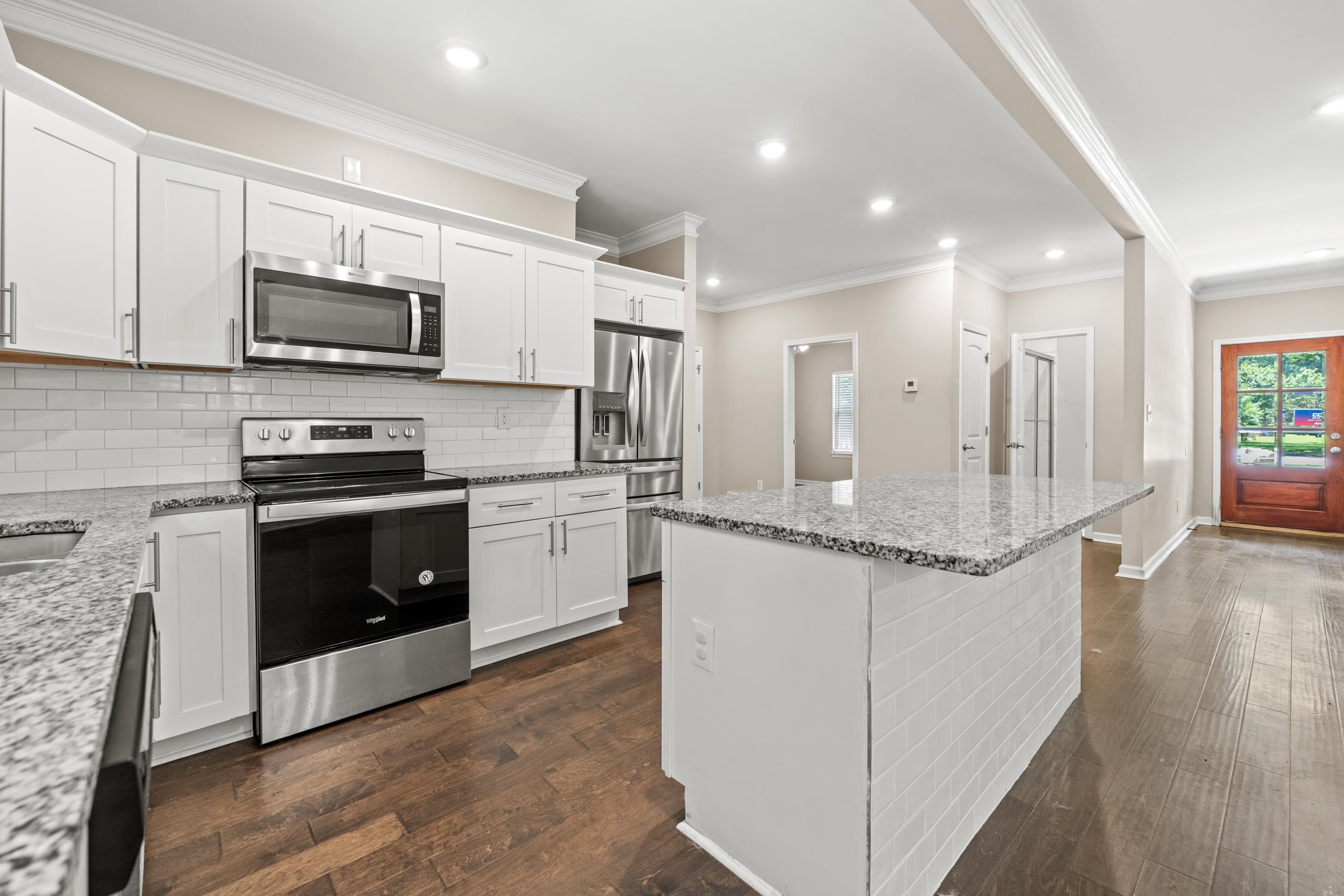 1255 Colonial Road Memphis, TN 38117 - Photo 9 of 30 Kitchen featuring white cabinetry, stainless steel appliances, granite countertops, a white subway tile backsplash, and wood-finish flooring