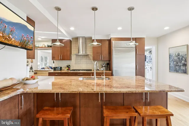a kitchen with stainless steel appliances granite countertop a sink a stove and chairs