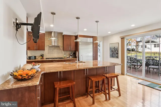 a kitchen with stainless steel appliances granite countertop a refrigerator a oven and a sink with wooden floor