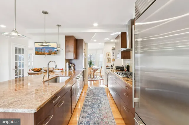 a kitchen with stainless steel appliances granite countertop a stove a sink a refrigerator and wooden cabinets