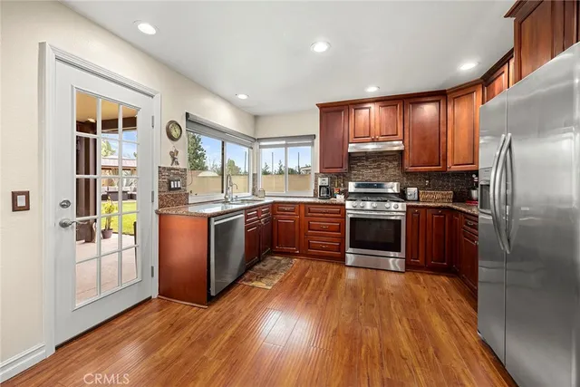 a kitchen with stainless steel appliances granite countertop a stove a sink and a refrigerator