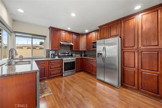 a kitchen with granite countertop stainless steel appliances a refrigerator cabinets and wooden floor