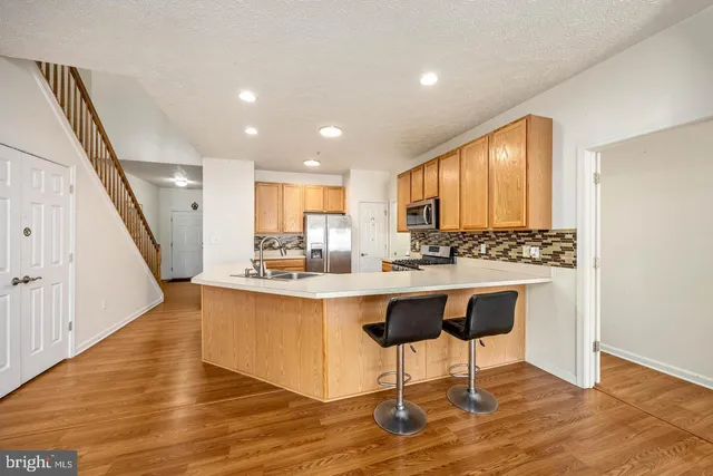a large white kitchen with wooden floor and stainless steel appliances
