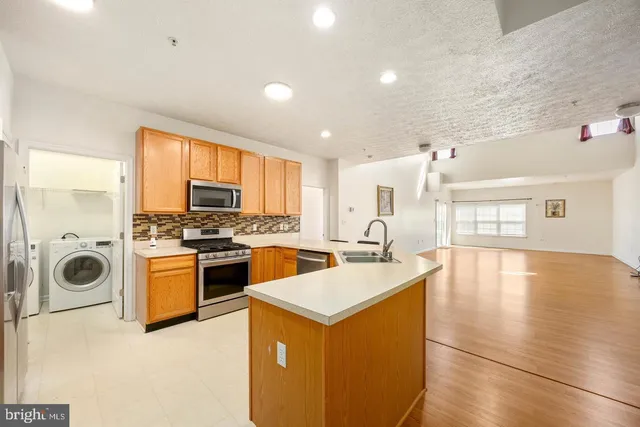 a large white kitchen with a sink a window and stainless steel appliances