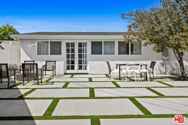 a view of a patio with couches and table and chairs with wooden floor and fence