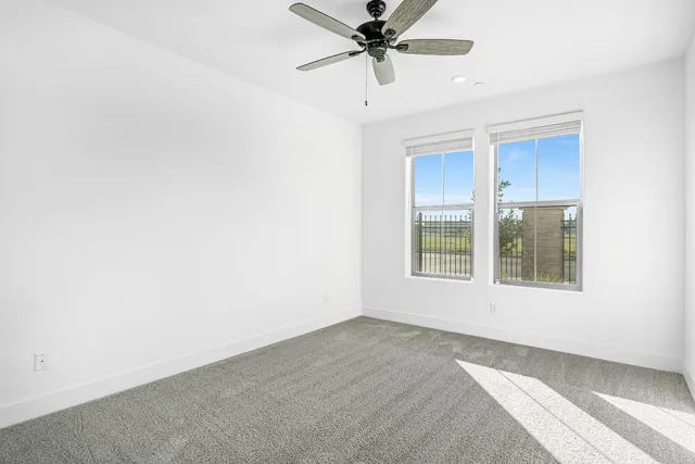 an empty room with a window and a ceiling fan