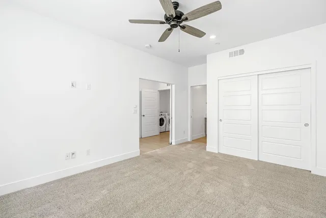 an empty room with closet and a ceiling fan