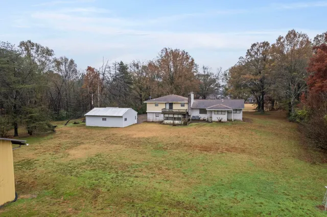 a tall yellow house with trees in front of it
