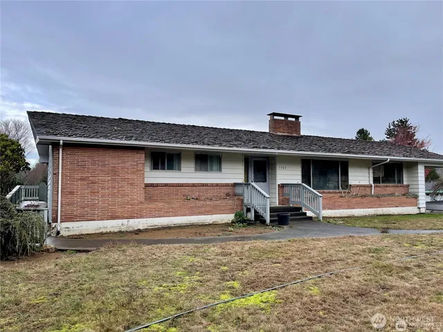 a view of a house with a barbeque and large trees
