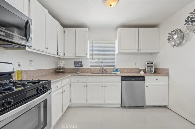 a kitchen with granite countertop white cabinets sink and stainless steel appliances
