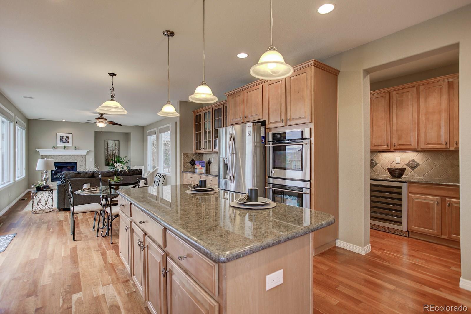 10879 Glengate Circle Highlands Ranch, CO 80130 - Photo 11 of 35 a kitchen with granite countertop a stove a sink a oven and a dining table with wooden floor