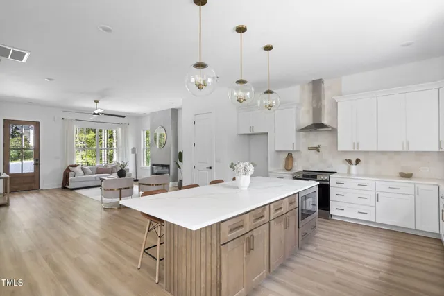 a kitchen with sink stove and white cabinets with wooden floor