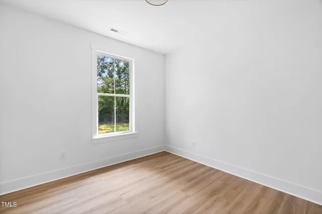 an empty room with wooden floor and window