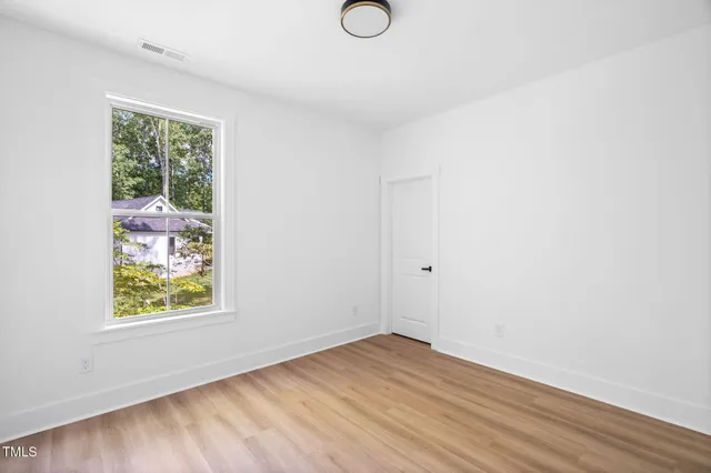 an empty room with wooden floor and window
