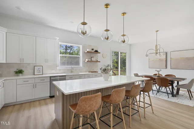 a view of a dining room and livingroom with furniture wooden floor a chandelier
