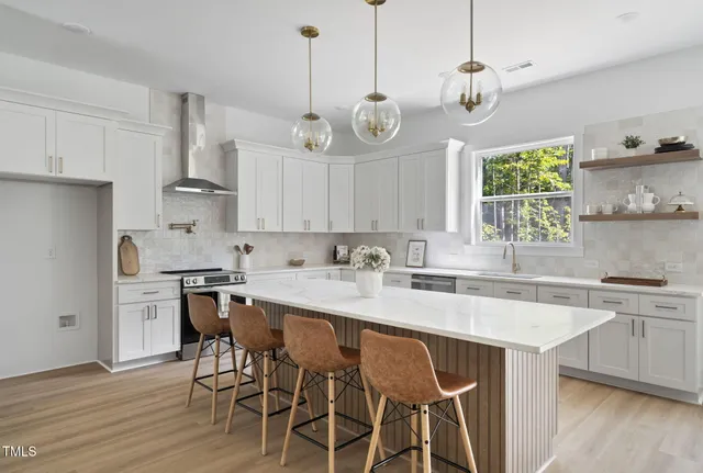 a kitchen with stainless steel appliances granite countertop a sink a stove a dining table and chairs with wooden floor