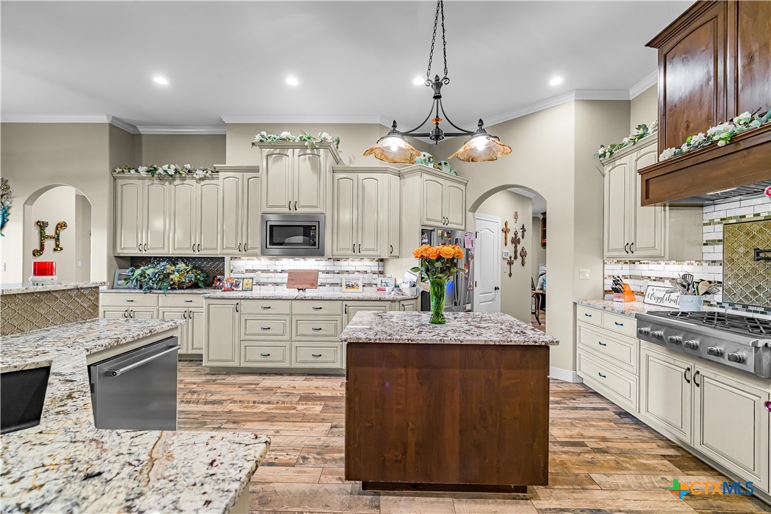 254 Sendera Loop Victoria, TX 77904 - Photo 22 of 48 a large kitchen with stainless steel appliances kitchen island granite countertop a stove a sink dishwasher and white cabinets with wooden floor