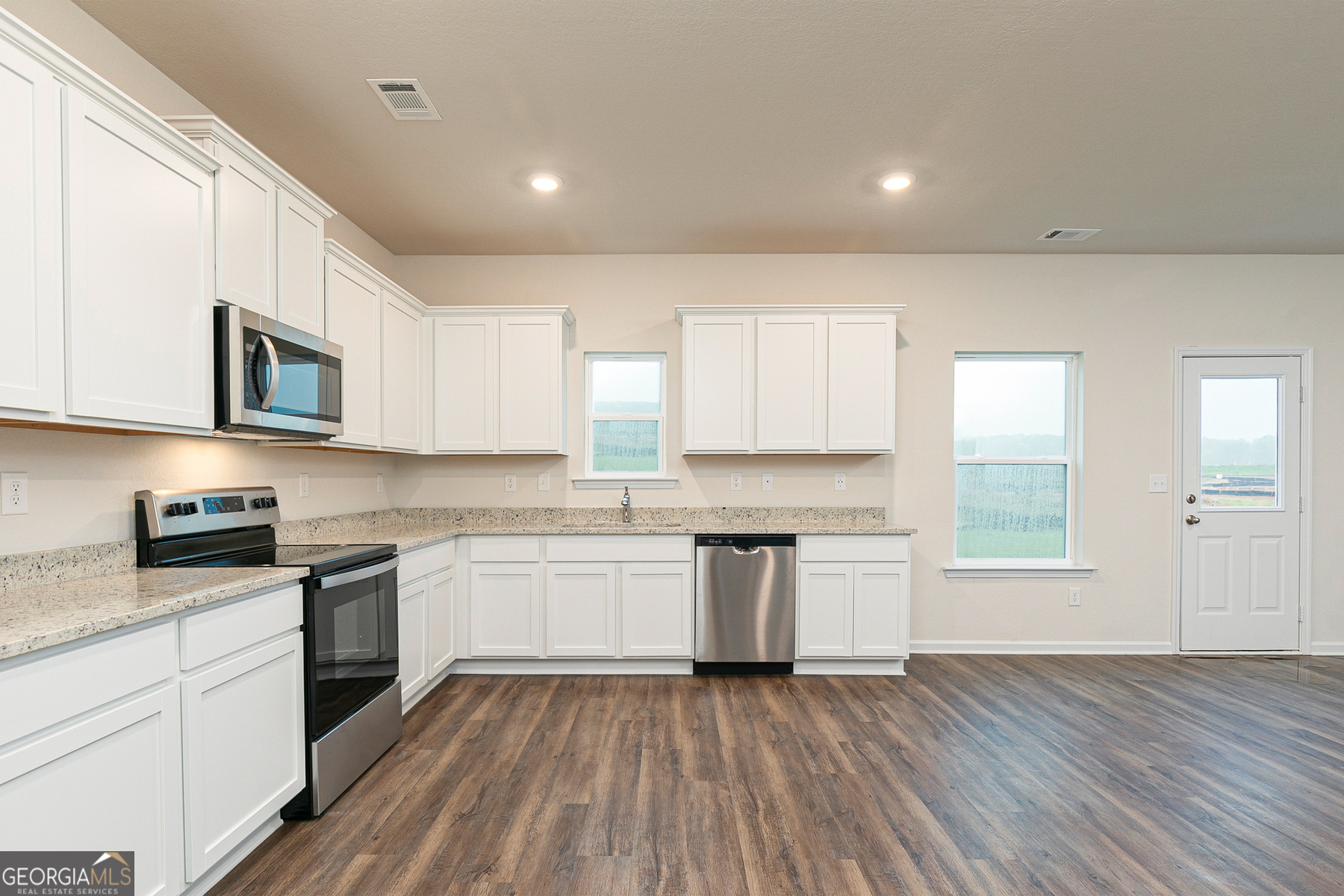 1513 Big Lane Locust Grove, GA 30248 - Photo 10 of 39 a kitchen with granite countertop white cabinets a sink a window and stainless steel appliances