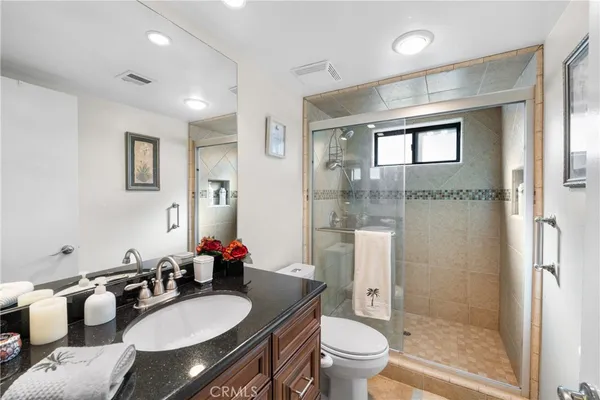 a bathroom with a granite countertop double vanity sink toilet and shower