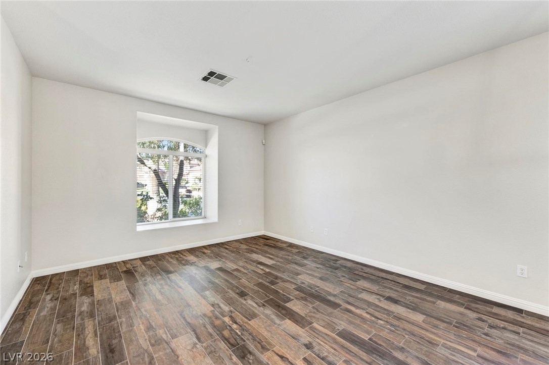 740 Aldo Rae Court, Unit NONE Henderson, NV 89052 - Photo 5 of 35 A well-lit room showcasing rich, wood-look tile flooring and an arched window offering green outdoor views.