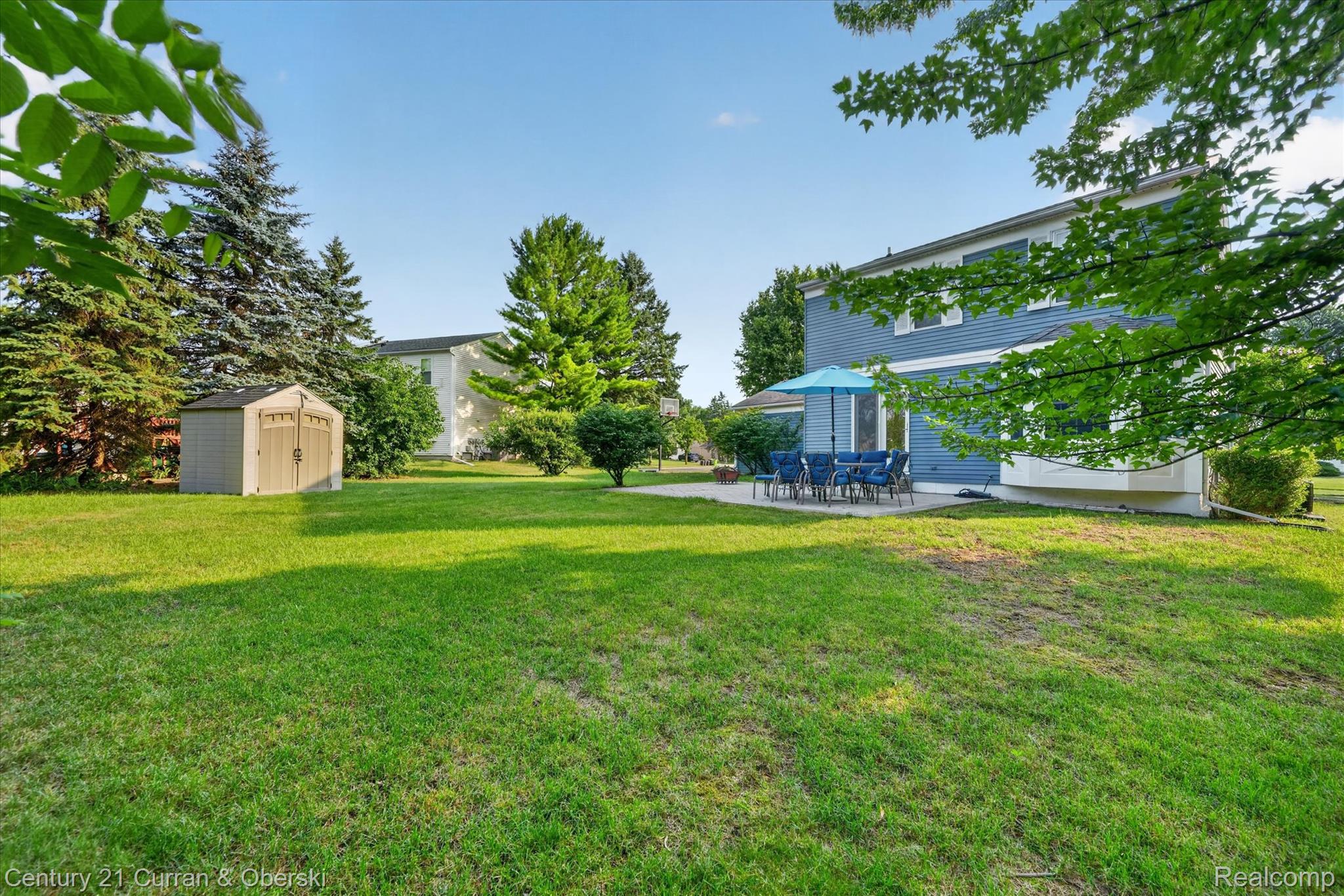 24525 Jamestowne Road Novi, MI 48375 - Photo 33 of 34 Expansive rear yard featuring a large patio, mature trees, and a utility shed