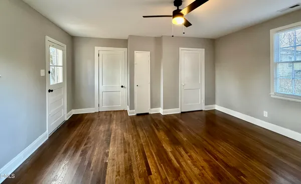 a view of an empty room with wooden floor and a window