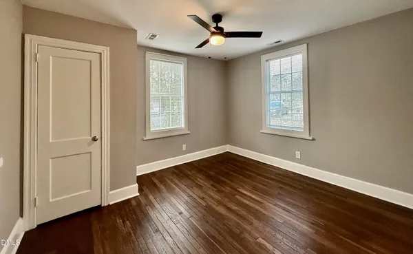 a view of an empty room with window and wooden floor