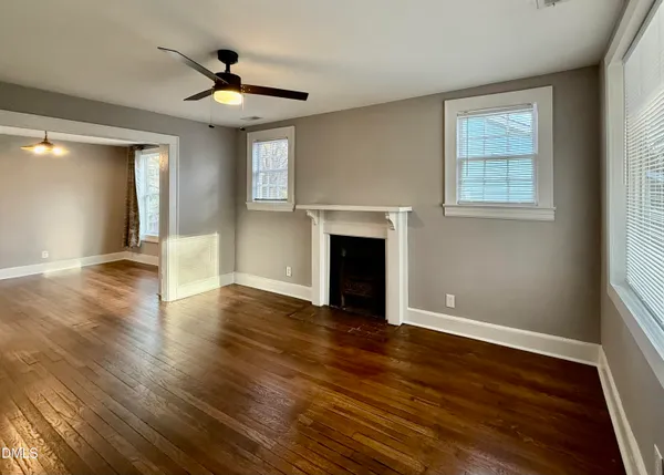 a view of empty room with wooden floor and fan
