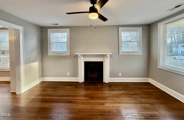 an empty room with wooden floor a ceiling fan and windows