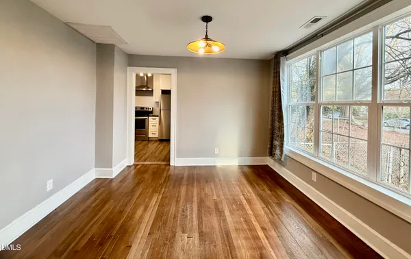 a view of empty room with wooden floor and fan