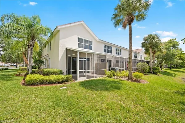 a view of a house with a yard and palm trees