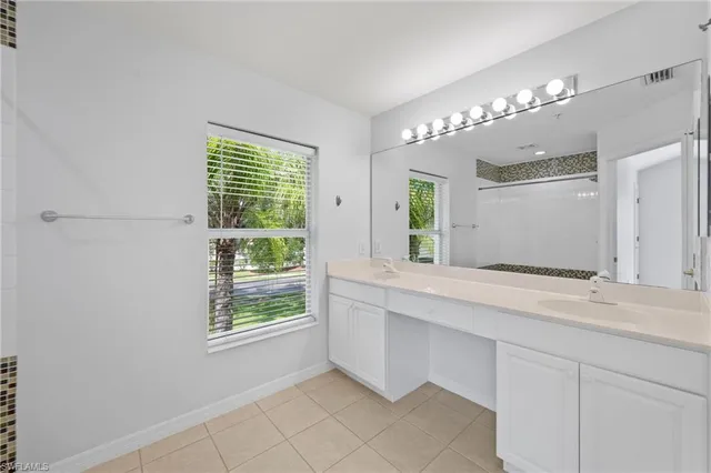 a spacious bathroom with a granite countertop sink a large mirror and a window
