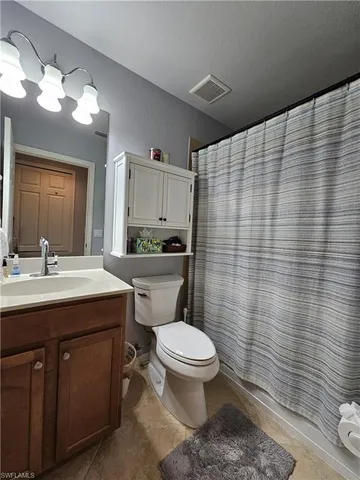 a bathroom with a granite countertop toilet sink and mirror