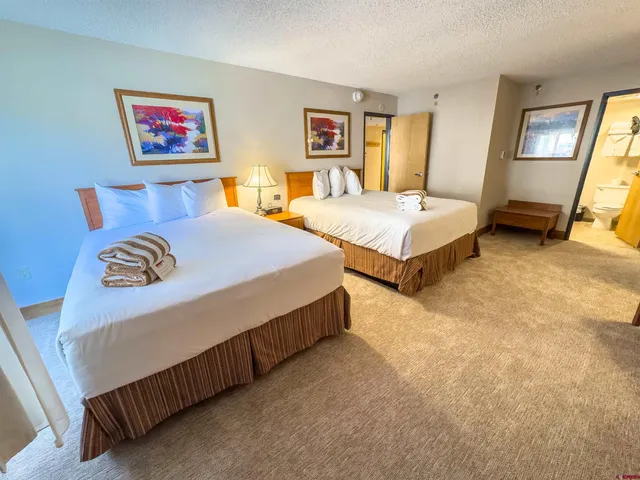 a bedroom with two bed and a mirror