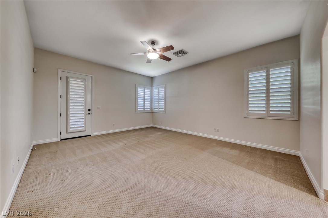 2122 Mooreview Street Henderson, NV 89012 - Photo 17 of 44 An airy bedroom with vaulted ceilings, featuring neutral carpeting and crisp plantation shutters for privacy and light control.