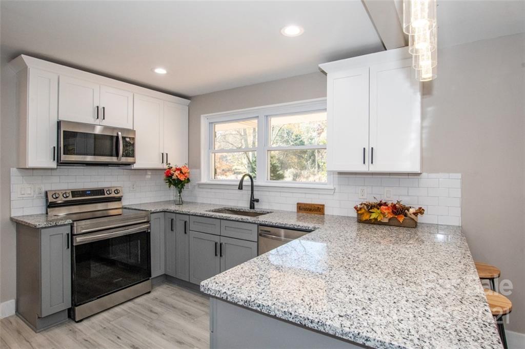 a kitchen with stainless steel appliances granite countertop a stove a sink and a microwave