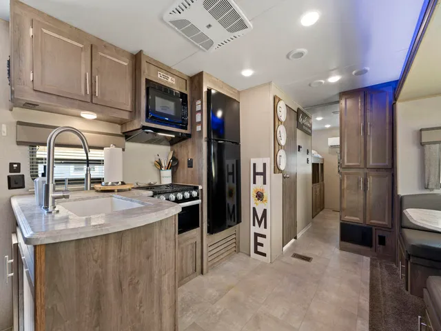 a kitchen with stainless steel appliances granite countertop a refrigerator oven a sink dishwasher and white cabinets with wooden floor