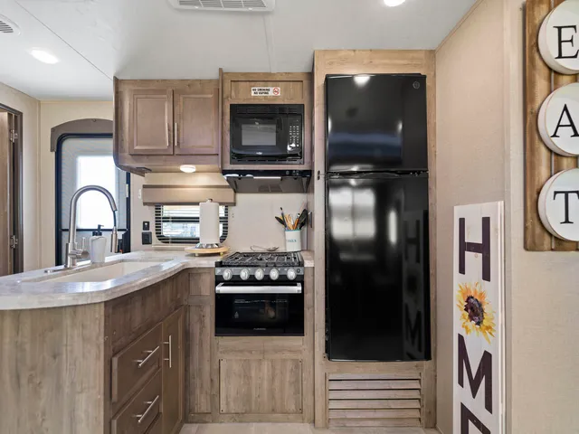 a kitchen with stainless steel appliances granite countertop a refrigerator a stove and a sink with wooden floor