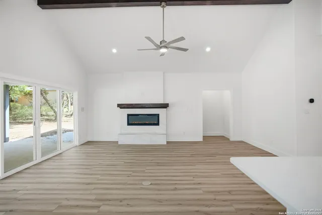 a view of empty room with wooden floor and fan
