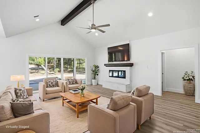 a living room with furniture floor to ceiling window and a flat screen tv