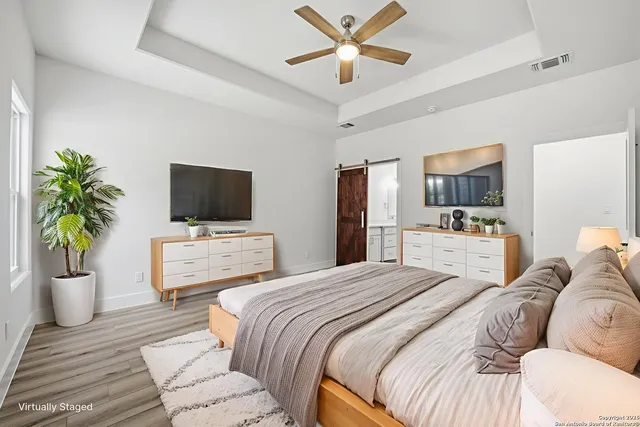an empty room with wooden floor chandelier fan and windows